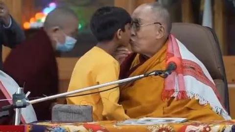 Dalai Lama besa a un niño en la boca